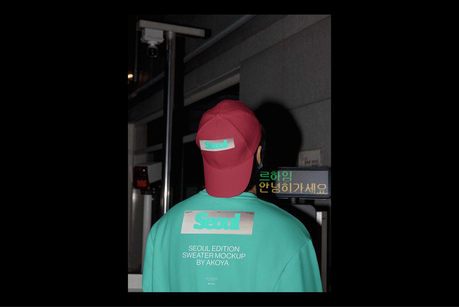 Mockup of a person in a teal sweater with Seoul graphic and red cap in an urban setting. Ideal for designers seeking trendy apparel graphics.