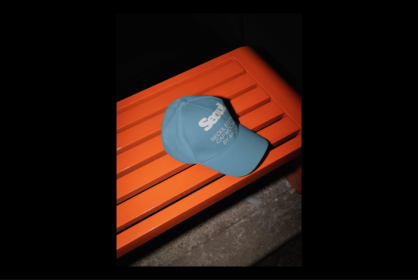 Blue cap with Seoul text on orange bench. Fashion mockup for designers. Minimalist style photography. Urban streetwear accessory design. High-quality graphic