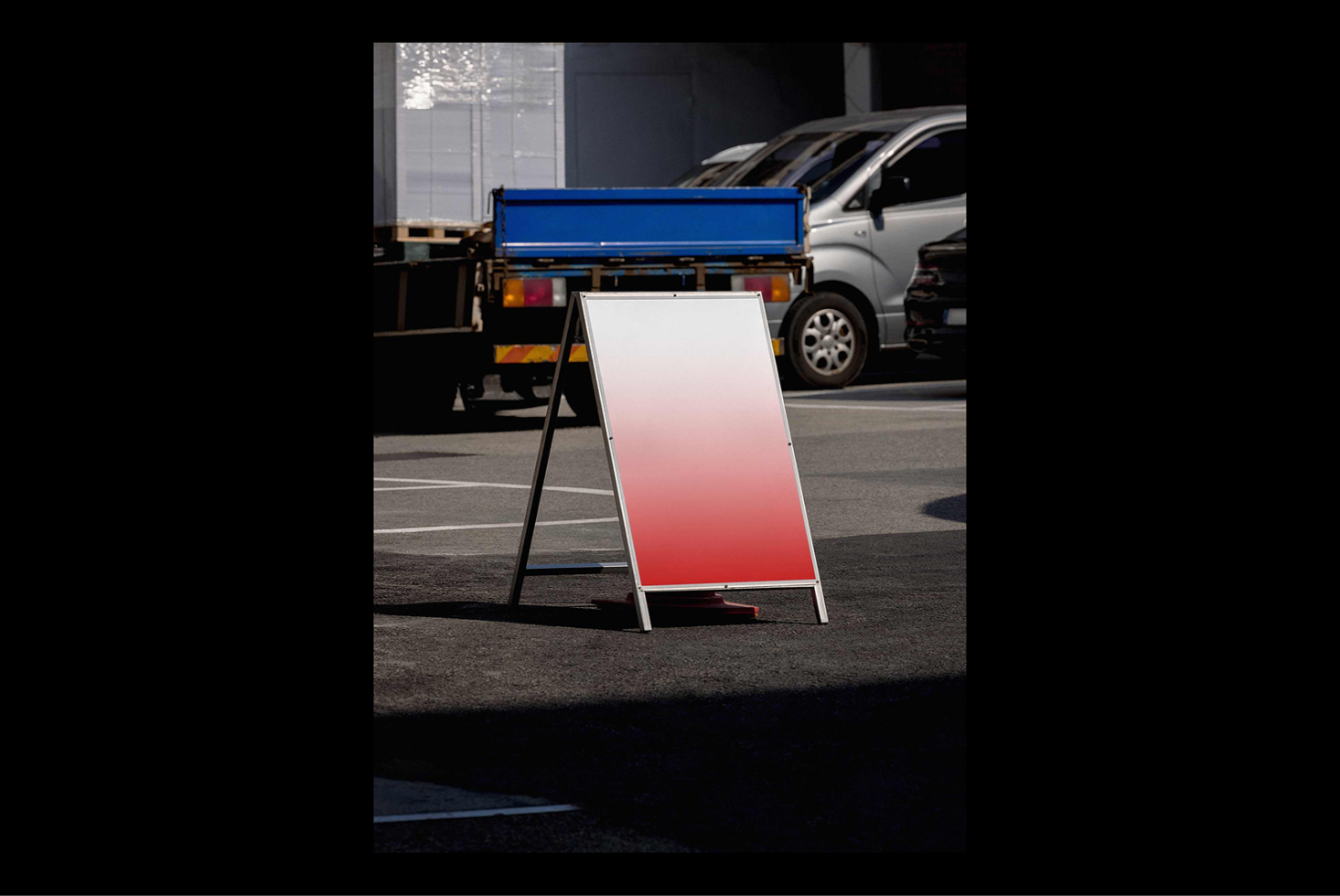 A-frame sign mockup with a red gradient background on parking lot. Perfect for advertising design templates, showcasing branding, street graphics.