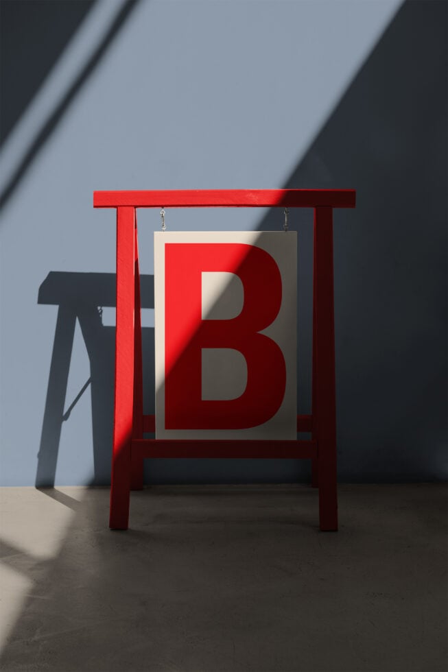 Red wooden B frame sign mockup on concrete floor with shadow