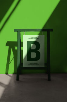 Dark frame holding light card with large green B on bright green backdrop