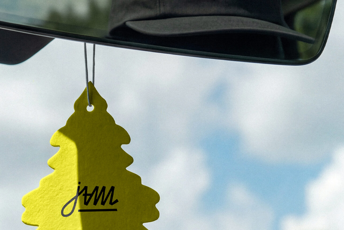 Lime green car air freshener hanging from rearview mirror outdoors