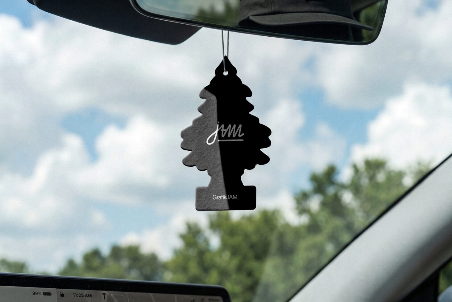 Black tree-shaped car air freshener hanging from rearview mirror in vehicle