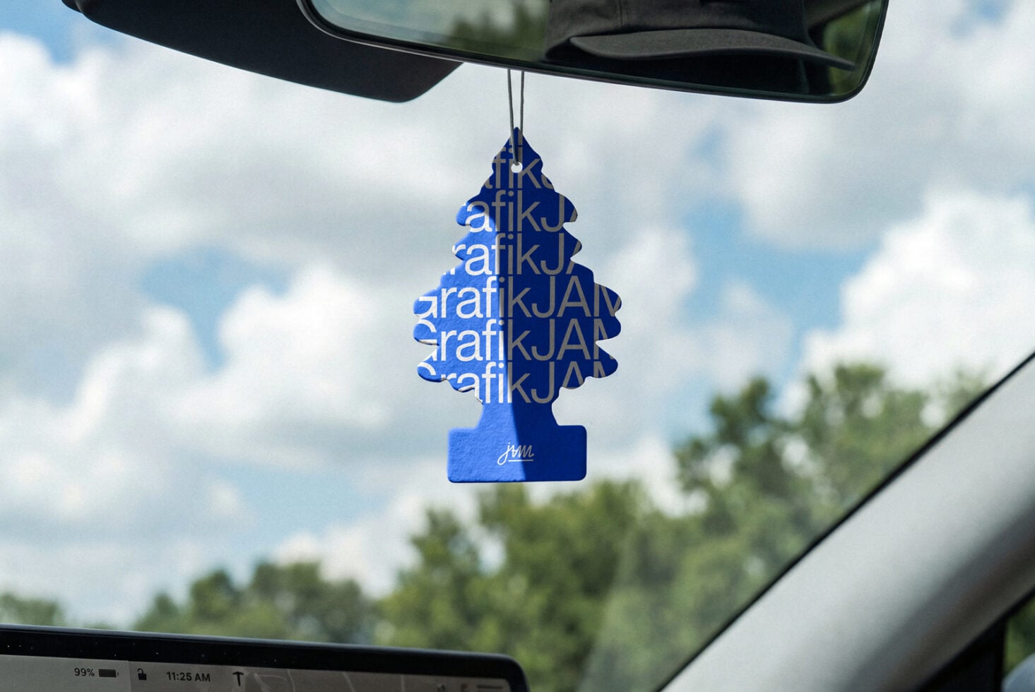 Blue tree air freshener with repeated text pattern hanging from car mirror