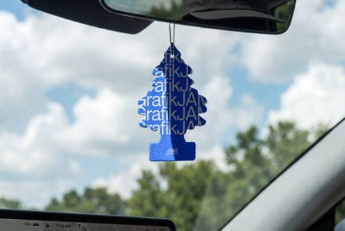 Blue tree air freshener with repeated text pattern hanging from car mirror