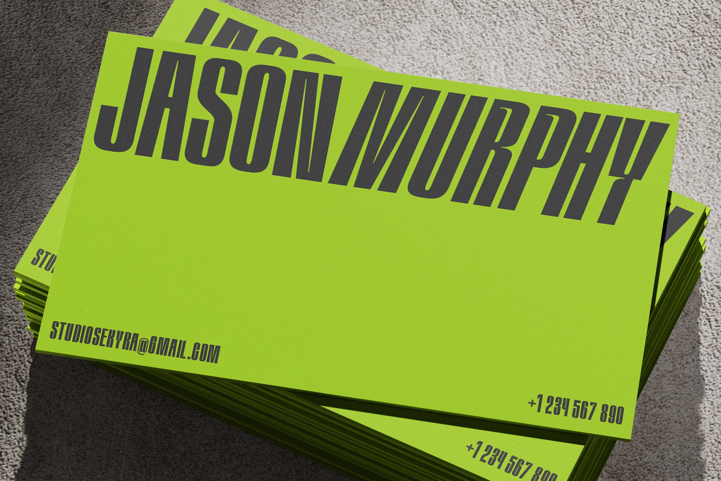 Neon yellow business cards stacked showing dark typography on textured surface