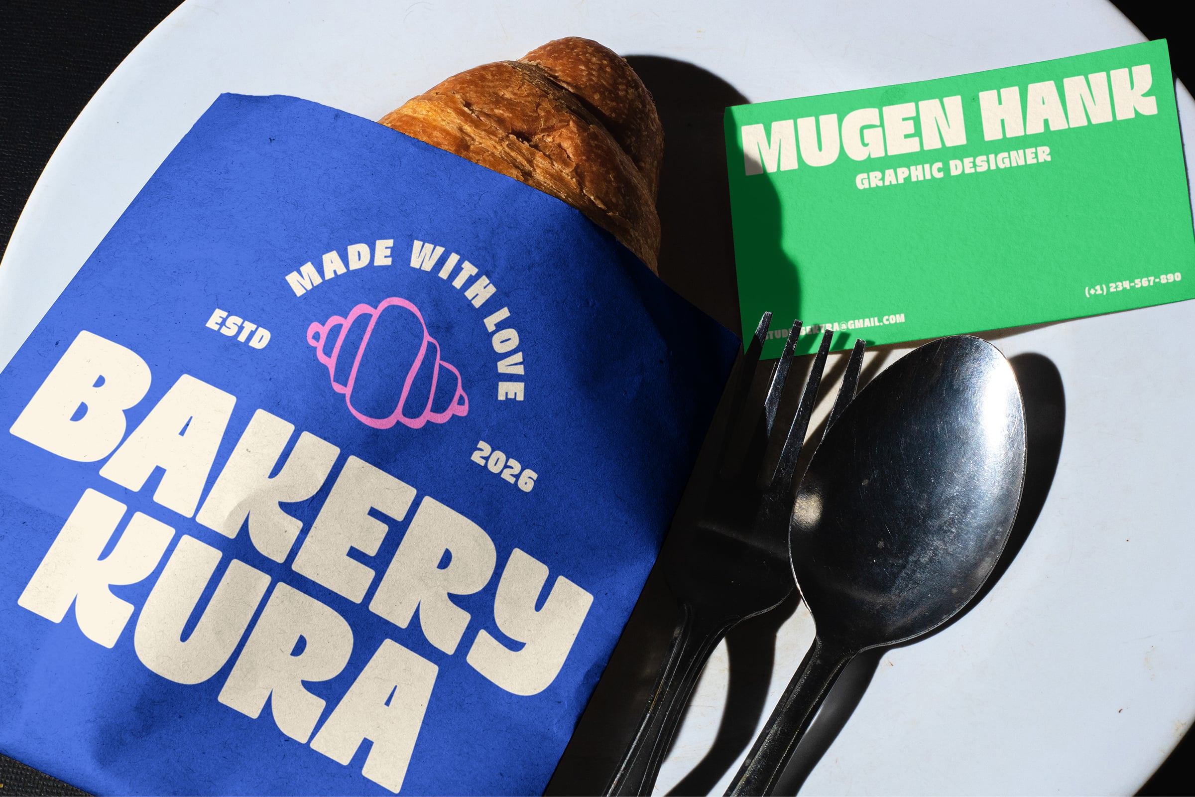 Blue bakery bag next to green business card with spoons on white plate