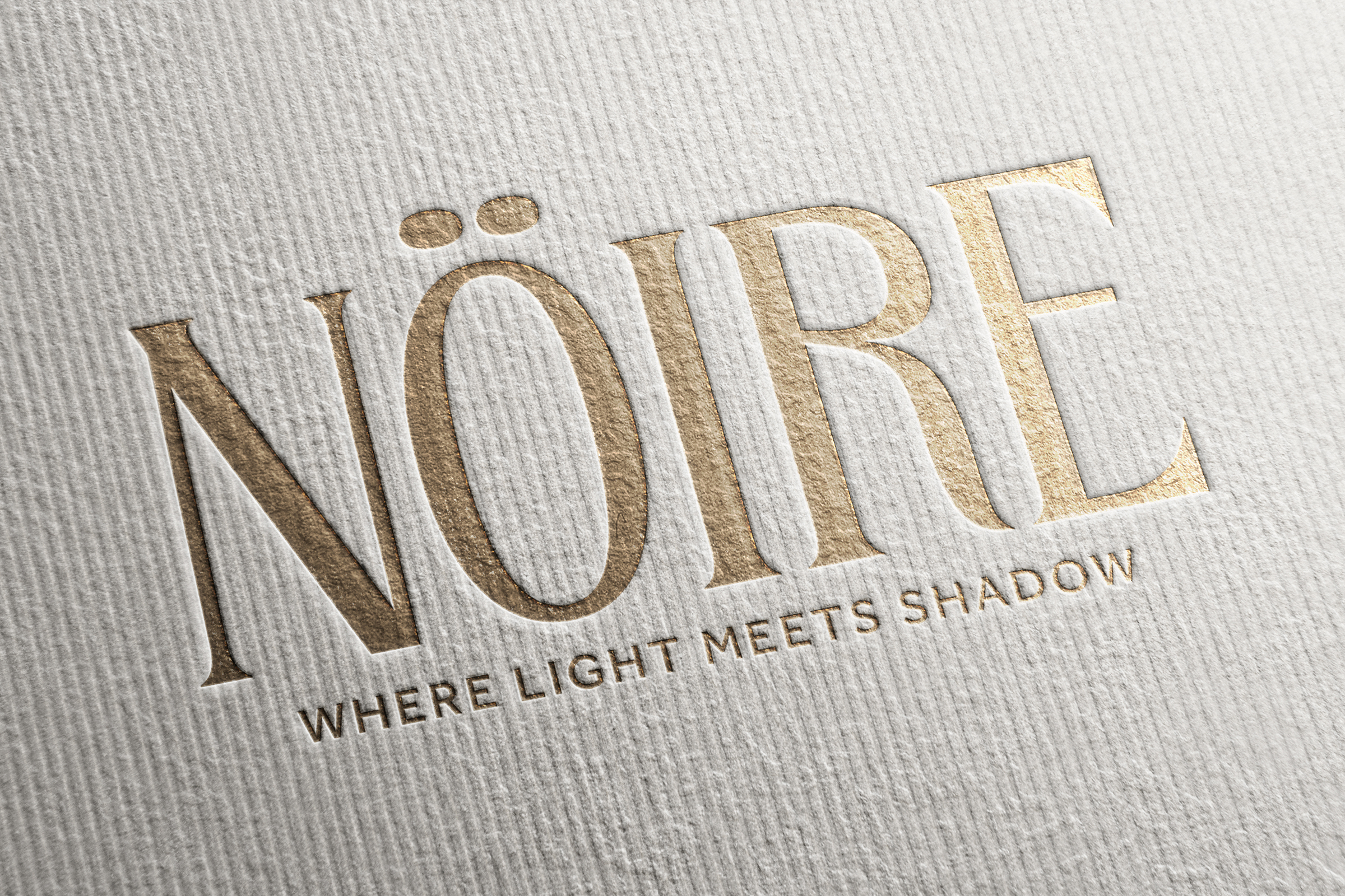 Gold embossed Noire logo with tagline on white textured paper