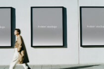 Woman walking past gallery wall with three framed displays featuring gray gradient backgrounds