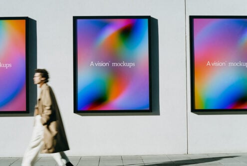 Woman in beige coat walking past three framed displays with colorful gradient backgrounds