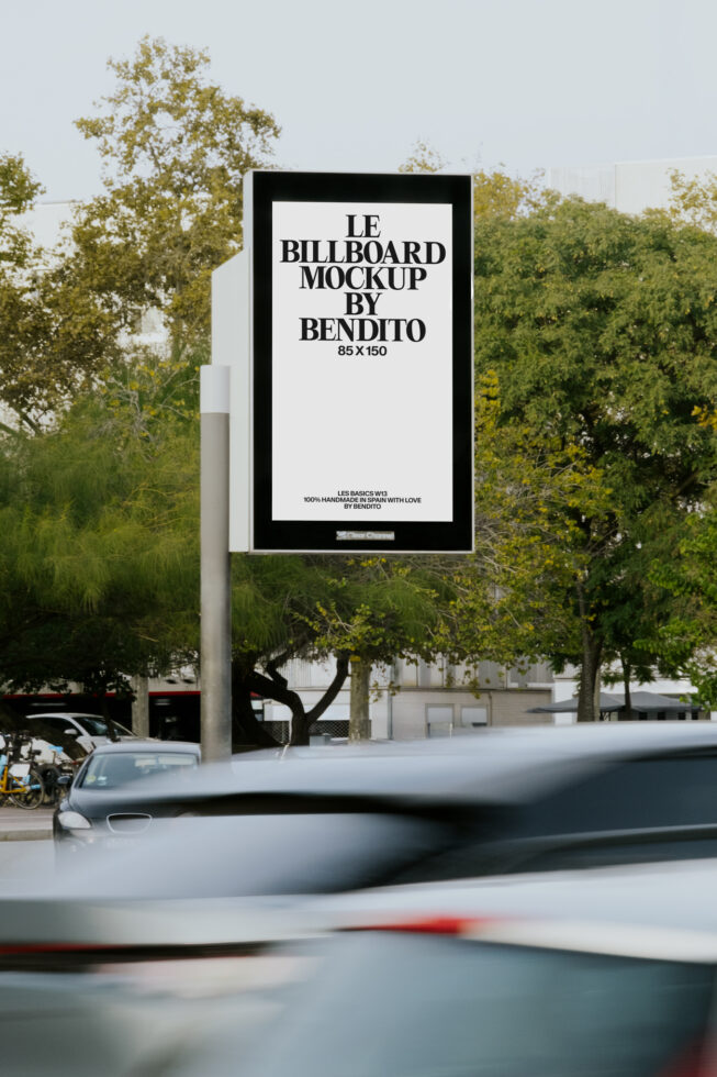 Outdoor billboard display with white panel, leafy trees blurred in background