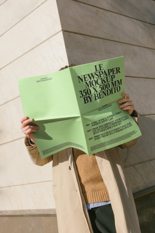 Person holding open lime green newspaper mockup with black typography, bright color