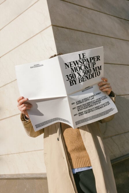 Person holding open white newspaper mockup with black text, clean minimal layout