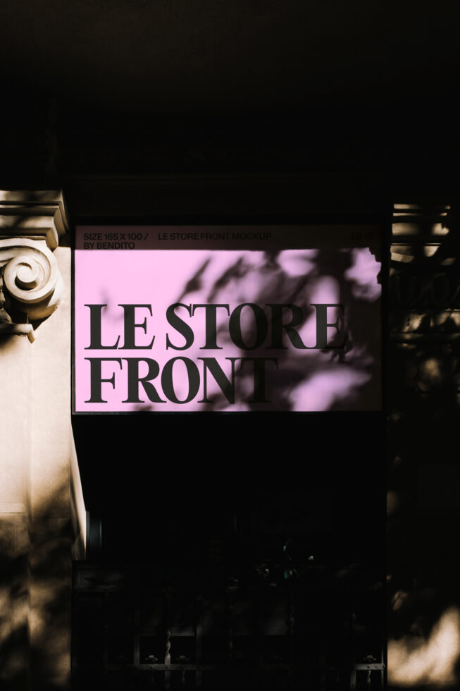 Neon pink illuminated storefront sign against dark night with ornate column