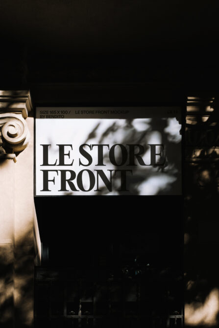 Storefront sign with serif typography on white background, architectural details visible
