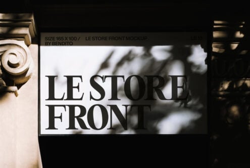 White storefront sign mockup with black serif text, ornate building columns framing