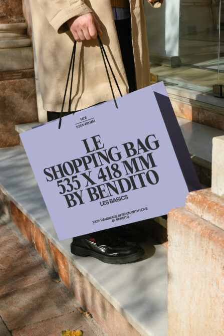 Lavender shopping bag with dark text held by person in cream colored jacket