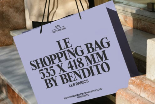Periwinkle shopping bag with bold typography resting on brick ledge outdoors