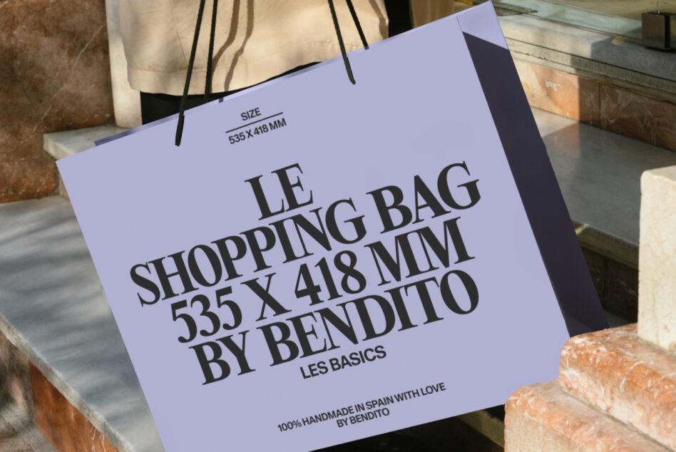 Periwinkle shopping bag with bold typography resting on brick ledge outdoors