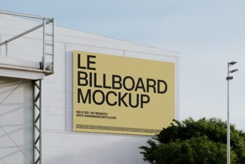 Yellow billboard with black text mounted on white industrial building wall