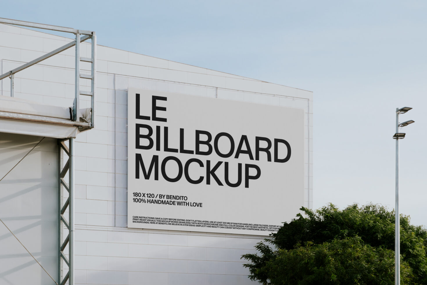 White billboard on industrial building with greenery below clear sky