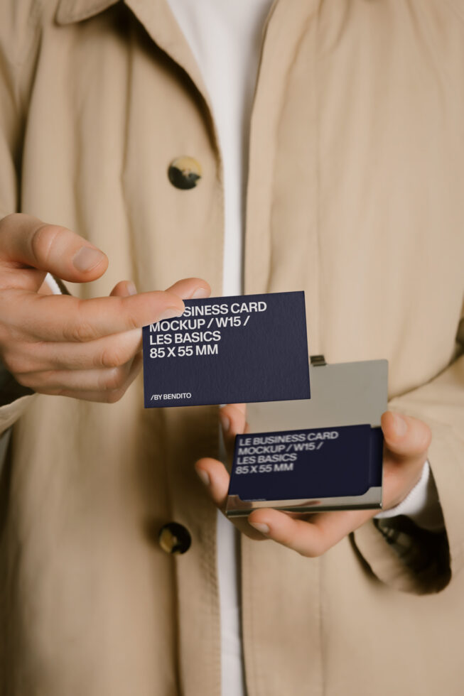 Person in beige blazer holding stacked dark blue business cards