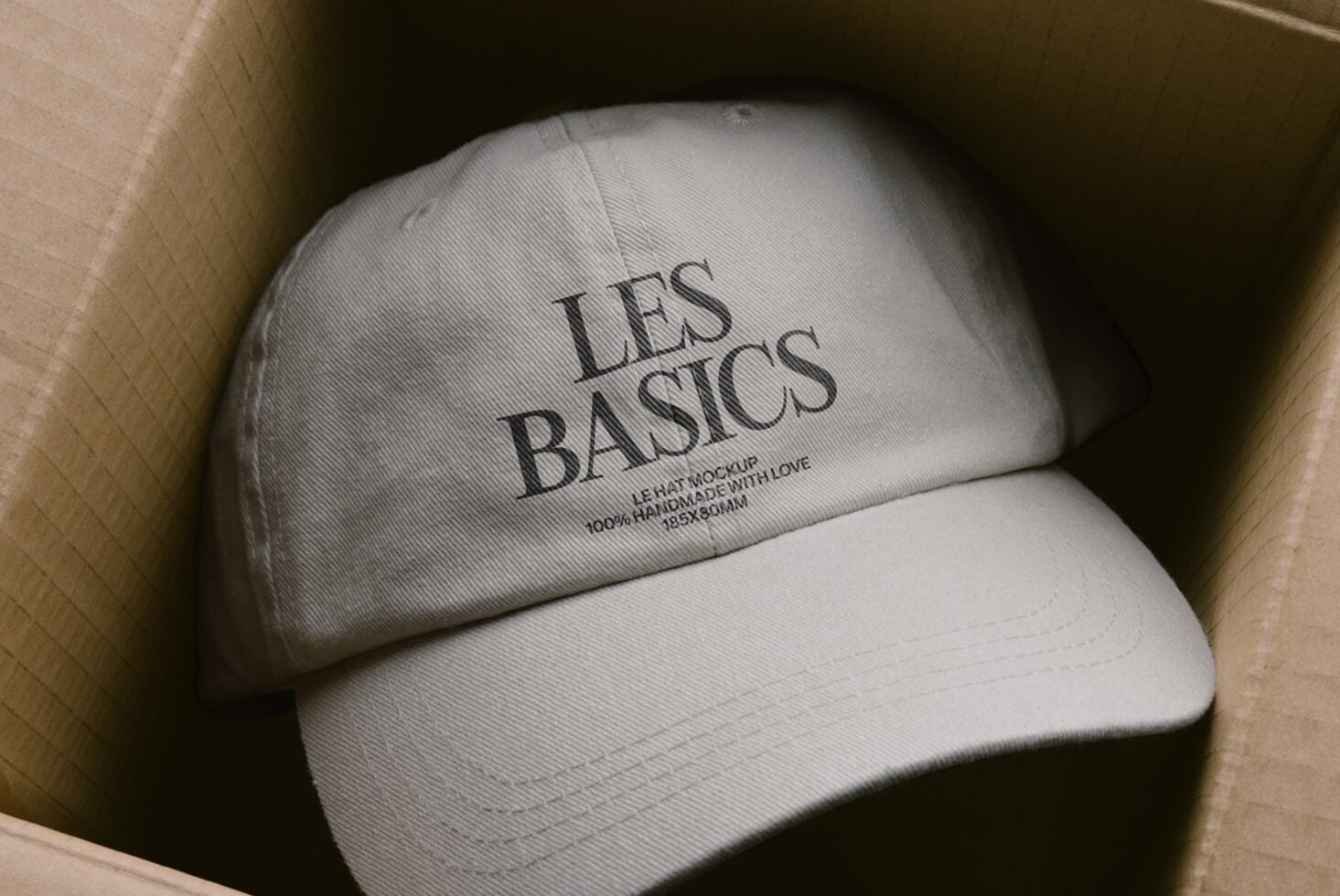 White embroidered cap nestled in kraft box with product details visible on fabric