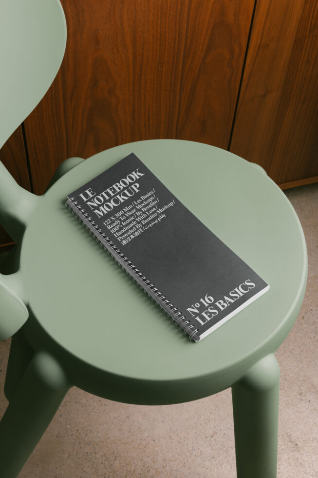 Dark spiral notebook mockup sitting on sage green round table with wood chair
