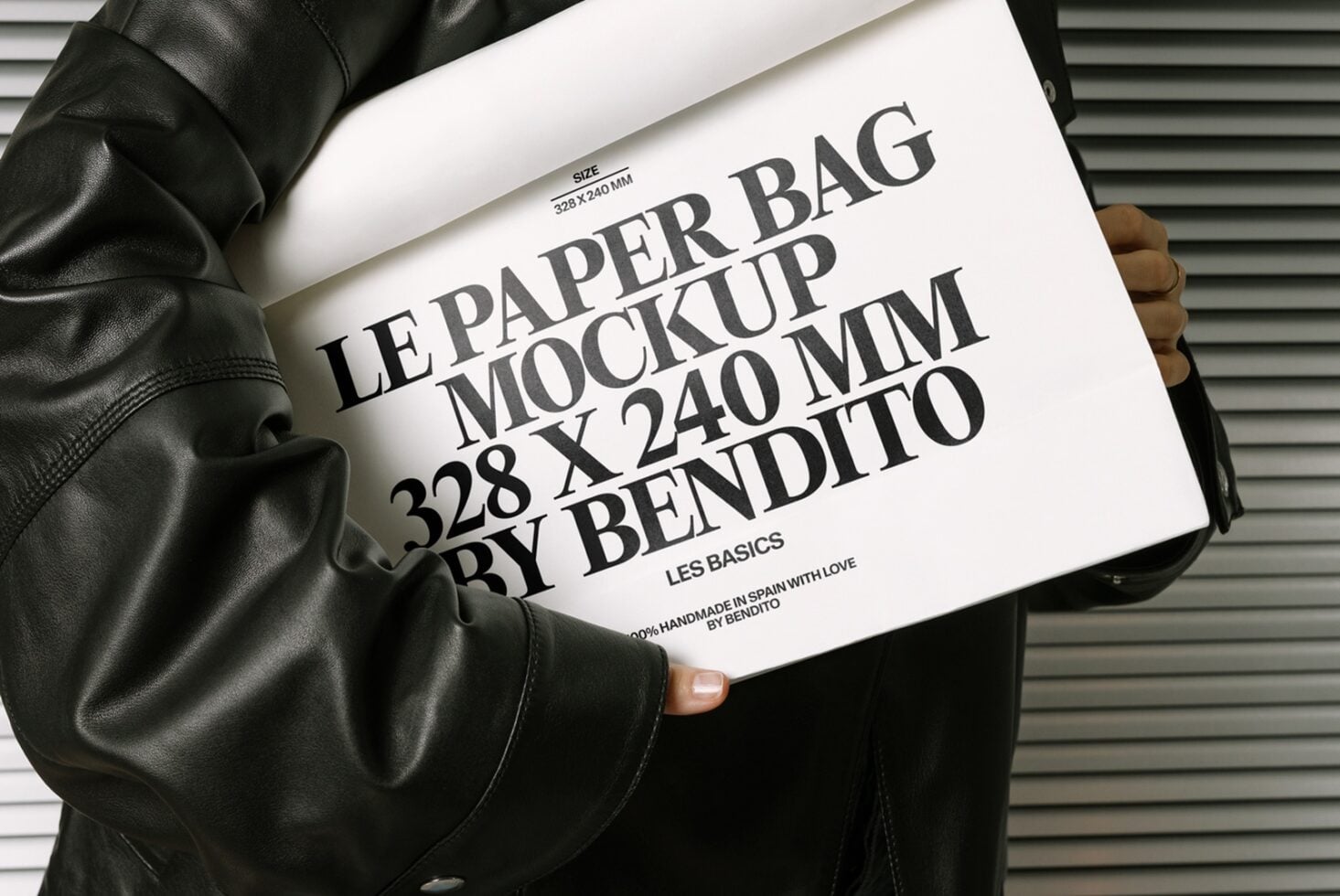 White paper bag mockup with black text on leather jacket against metal wall