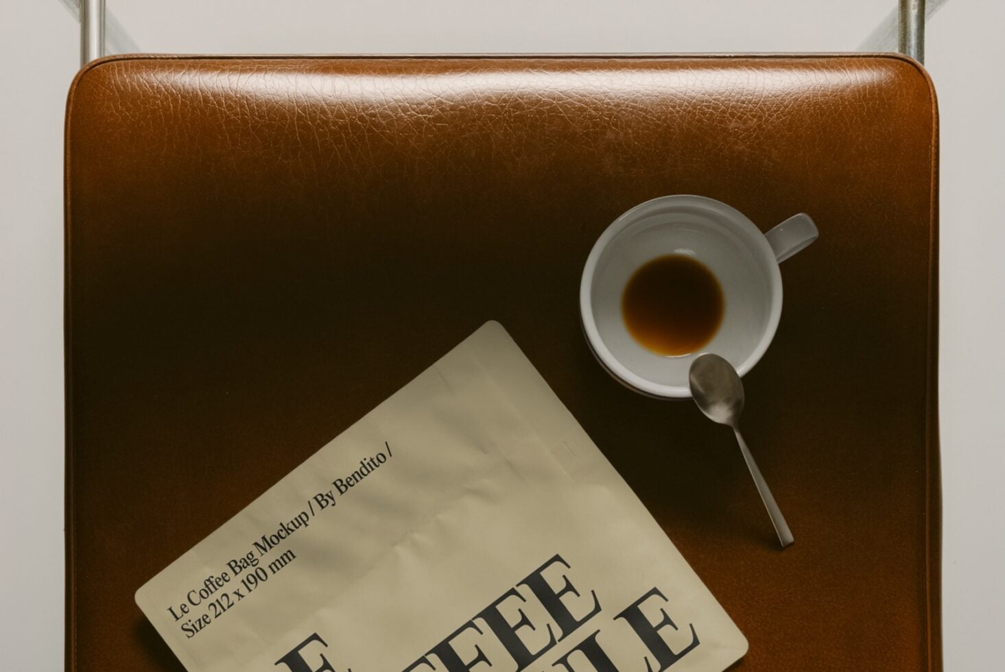 Top down view of tan leather bag holding espresso cup with saucer plus Le Coffee Bag card