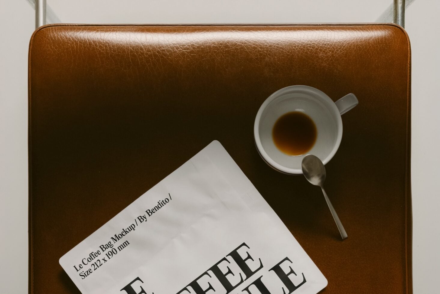 Top down view of tan leather bag holding espresso cup with saucer plus Le Coffee Bag card