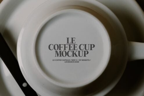 Overhead shot of stacked white ceramic cups with Le Coffee Cup Mockup text printed on bottom