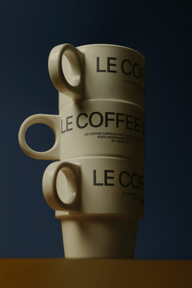 Stacked cream ceramic mugs with Le Coffee text on navy background