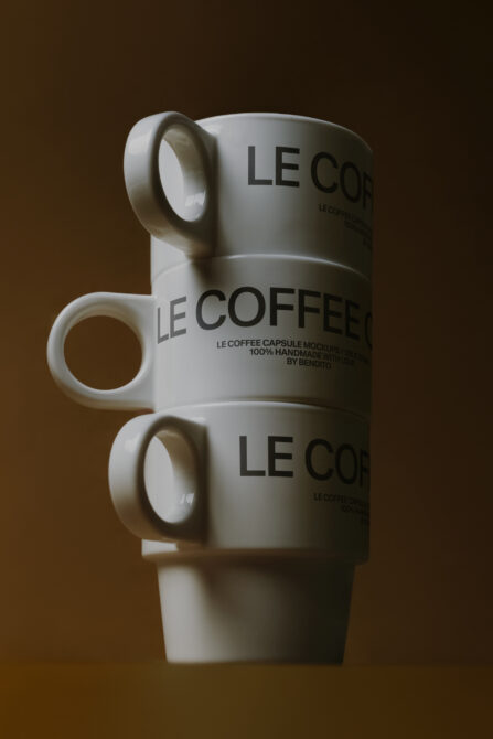 Stacked white ceramic mugs with Le Coffee text on brown background
