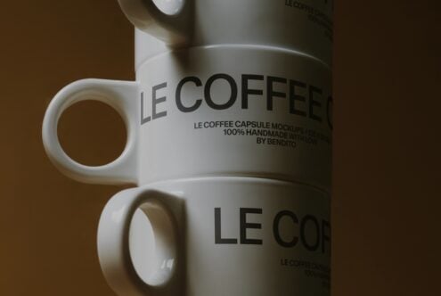 Close up of white mug with Le Coffee Capsule Mockup text on brown