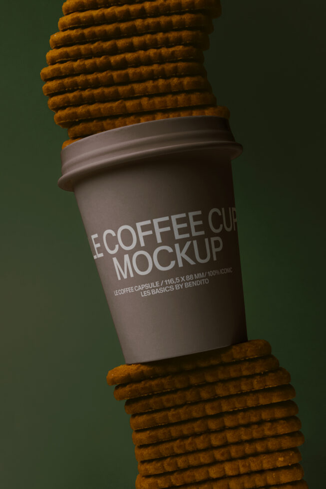 Dark brown paper cup stacked between waffle cookies on green backdrop