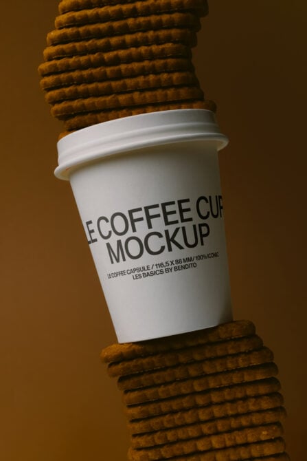 White paper cup sandwiched between crispy waffle cookies on warm tan background