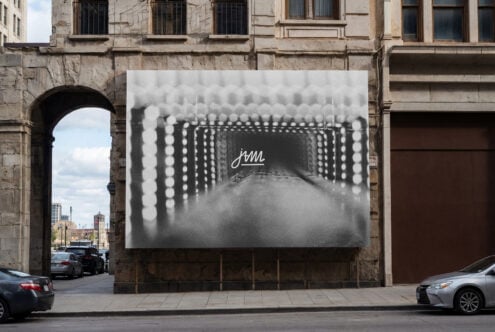 Large billboard on historic building featuring monochrome architectural tunnel with delicate jam text