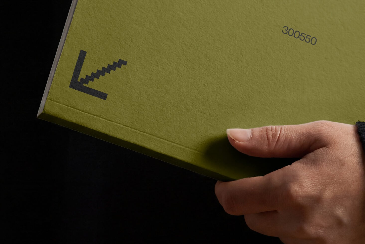 Hand holding lime green hardcover book with pixelated cursor icon design