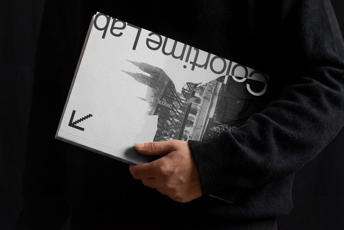 Black magazine held in hands with city architecture photo printed on cover