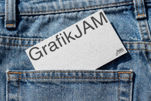 Light business card showing GrafikJAM text with small jWML signature on denim