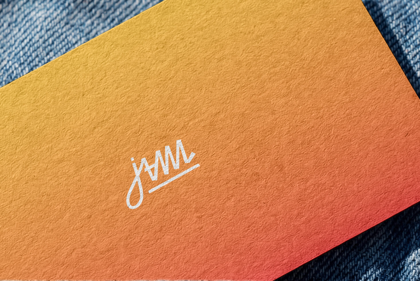 Yellow to coral gradient business card with white script logo on denim