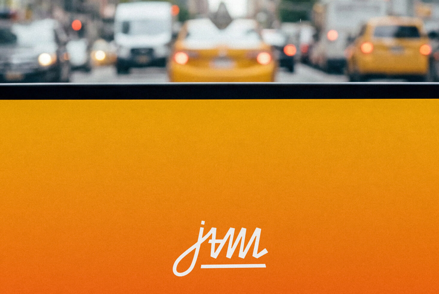 NYC street scene reflected above orange color block with cursive jam logo