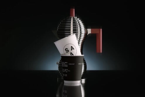 Coffee cup mockup with brand logo, chrome equipment, burgundy accent pieces visible