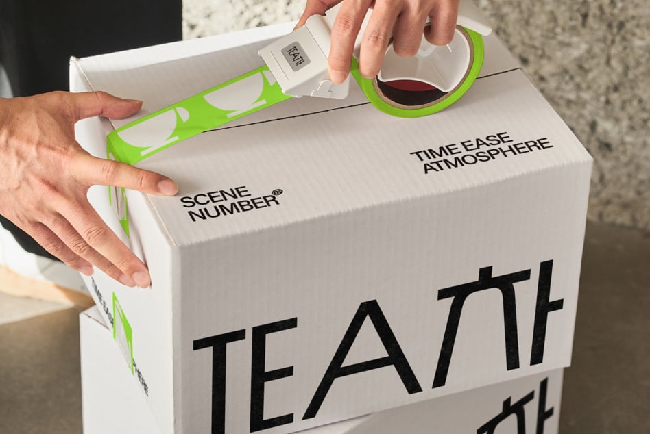 Person unrolling green tape from white box stamped with branding