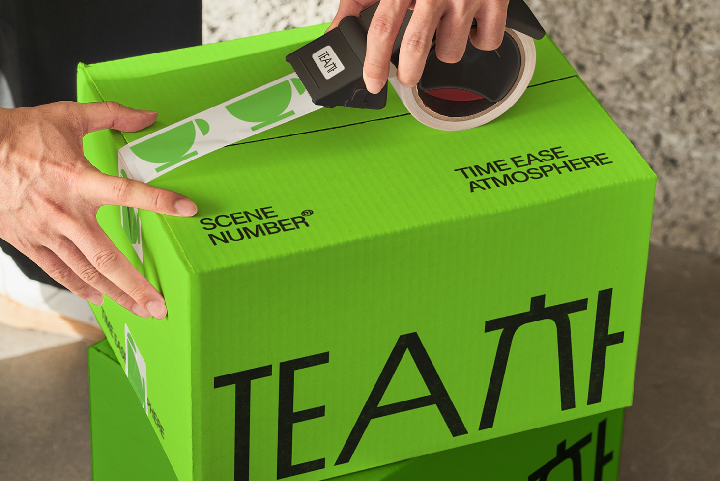 Hands opening bright green box with TEATT typography, tape dispenser visible