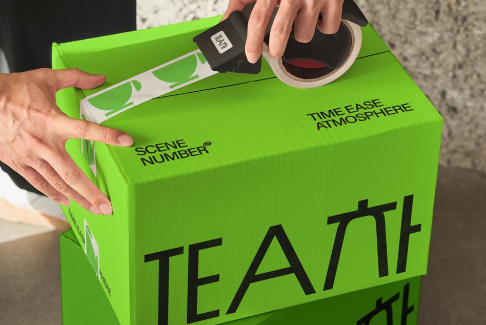 Hands opening bright green box with TEATT typography, tape dispenser visible