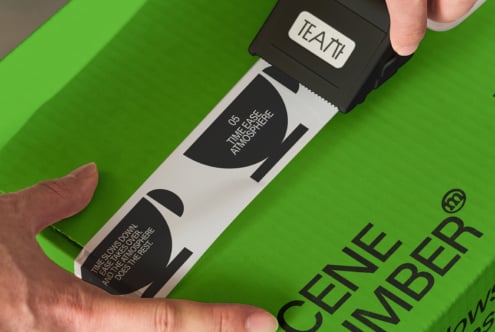 White tape dispenser with black TEATT label rolling over green surface