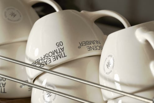 White ceramic mugs in close-up showing handle curves with logo placement