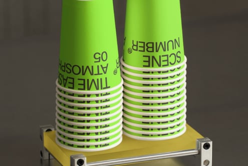 Bright lime cups stacked with white bands, displayed on yellow platform with metallic stand